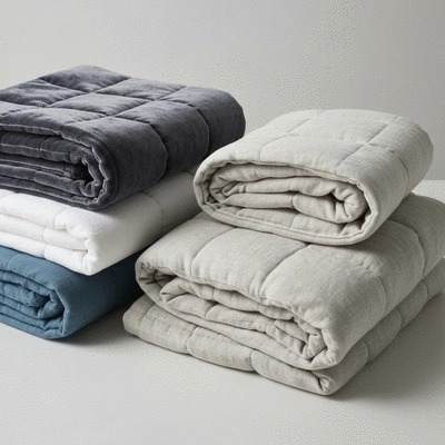 Various weighted blankets in different colors and textures, neatly folded